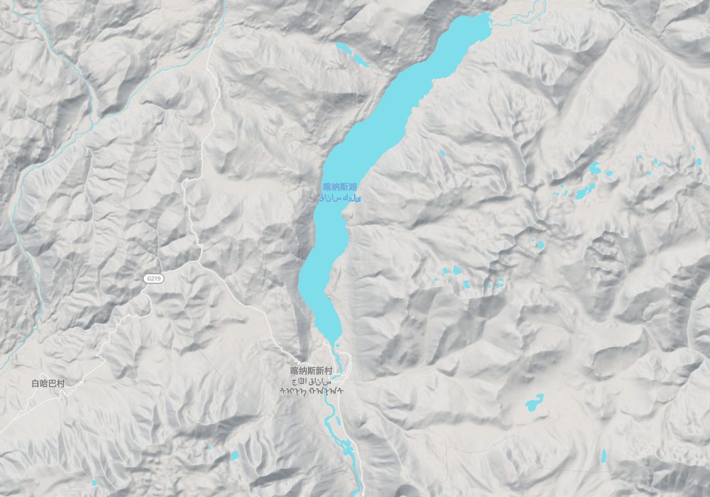 Kanas Lake fills a valley in the Altai Mountains and drains from its south end as the Kanas River, with Kanas New Village at the outlet; hillshade